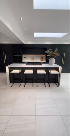 a kitchen with an island and stools in the center, surrounded by white tile flooring