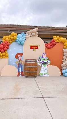 an outdoor area with balloons and decorations on the wall, including a barrel for beer