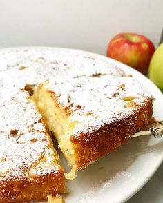 a white plate topped with a piece of cake next to an apple