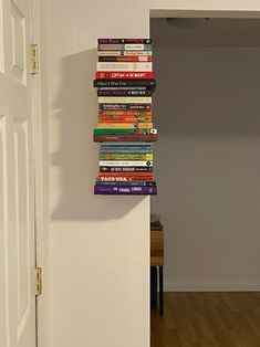 a stack of books sitting on top of a white wall next to a door in a room