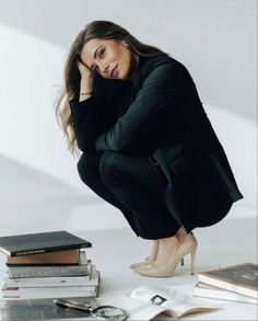 a woman kneeling down next to some books