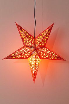 an origami star light hanging on a wall