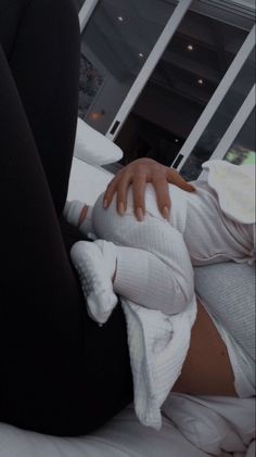 a woman laying on top of a bed covered in white blankets