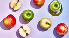 an assortment of apples are arranged on a white surface, including one green and one red