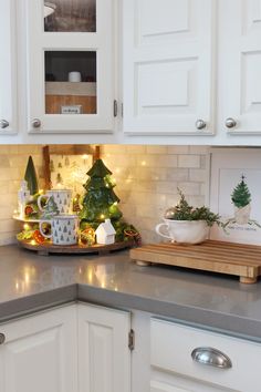 a kitchen counter with white cabinets and christmas decorations on the counter top, along with a cutting board