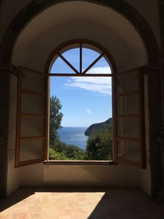 an open window with a view of the ocean and trees outside in front of it