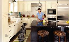 a woman standing in a kitchen next to a dog