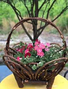 a basket filled with pink flowers sitting on top of a yellow table next to a tree