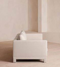 a white couch sitting on top of a hard wood floor next to a tall wall