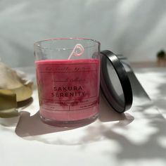 a pink candle sitting on top of a table next to a container with a black lid