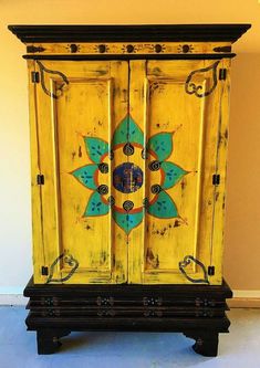 an old cabinet painted yellow and green with designs on the doors