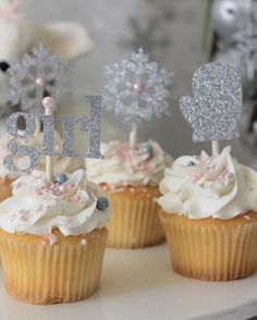 three cupcakes with frosting and sparkle decorations on top are sitting on a table