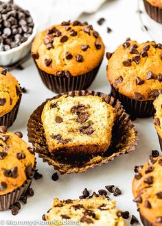 muffins with chocolate chips in the middle on a white surface next to other muffins