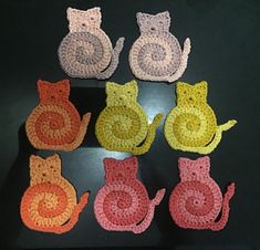 six crocheted cats sitting next to each other on top of a black table