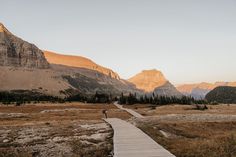 a person walking down a wooden path in the mountains with a mountain range in the background