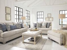 a living room filled with white furniture and lots of windows on top of the walls