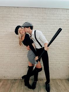 a man and woman dressed up as baseball players kissing each other while holding bats in front of a brick wall