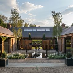 two horses are standing in the middle of a courtyard with plants and trees around it