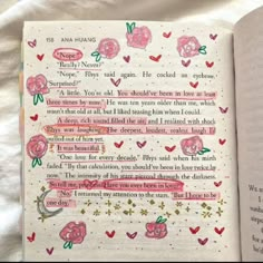 an open book with pink flowers and writing on the pages is sitting on a bed