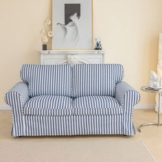 a blue and white striped couch sitting in a living room next to a painting on the wall