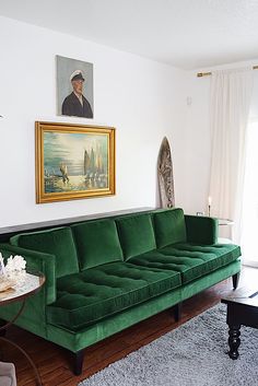 a living room with a green couch and painting on the wall