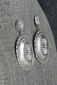 These sterling silver earrings were made by Navajo silversmith Terry Charlie. The back of one earring is signed T. Charlie and stamped sterling.Length: 2 1/4"Width: 1 1/2"Free shipping on all orders! We ship with USPS and always include tracking. All orders ship within a day of payment.Returns are accepted up to 30 days after you receive your order. Just send us a message. Our shop offers cash back or store credit. The item must be returned in new condition. Decorative Silver Earrings As Gift, Sterling Silver Concho Dangle Jewelry, Silver Concho Earrings As A Gift, Silver Concho Earrings For Gift, Elegant Silver Concho Earrings, Silver Dangle Earrings With Concho, Silver Concho Drop Earrings, Southwestern Sterling Silver Concho Jewelry, Silver Concho Dangle Earrings