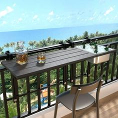 there is a table with two glasses on it next to the ocean and palm trees