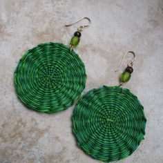 These are vibrant green earrings made with iraca fiber. Iraca is lovely and lightweight. Iraca fiber - The discs are hand woven, and no two are exactly the same. Source: Fallen leaves from Iraca palm plants in South America. Color: Two shades of green Iraca disc diameter: 2 inches  Accent beads: Green frosted glass and wood Earring length: 3 inches Ear wire: 14k gold-filled Green Handmade Eco-friendly Jewelry, Fair Trade Green Jewelry For The Beach, Bohemian Green Circular Earrings, Green Bohemian Circle Earrings, Traditional Green Jewelry For Beach, Handmade Green Round Earrings, Green Drop Earrings For The Beach, Green Drop Earrings For Beach, Green Bohemian Woven Earrings