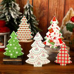 three small christmas trees sitting on top of a wooden table next to other ornaments and decorations