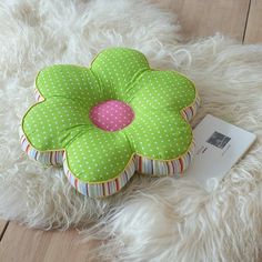 a green flower shaped pillow sitting on top of a white rug