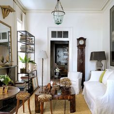 a living room filled with furniture and a clock on the wall next to a doorway