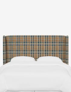 an upholstered headboard on a bed with white linens and plaid sheets