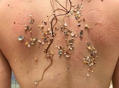 the back of a woman's body covered in shells