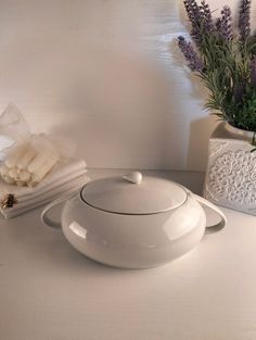 a white bowl sitting on top of a table next to a potted plant