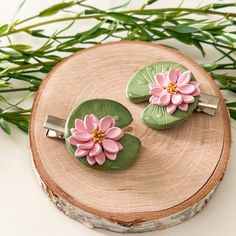 two pink flowers are sitting on top of green leafy brooches in front of some grass