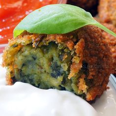 a close up of a piece of food on a plate with sauce and a green leaf