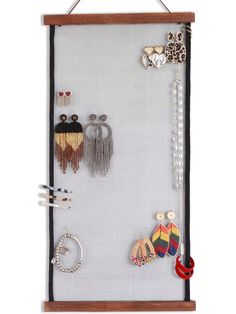 a wall hanging with earrings and other items on it's display board, which is made out of wood