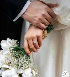 the bride and groom are holding each other's hands with their wedding rings on them