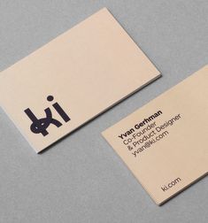 two business cards sitting next to each other on top of a gray surface with black and white logos