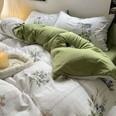 an unmade bed with pillows and a candle on it