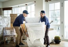 two men are moving boxes in the living room