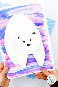 someone holding up a polar bear cutout with watercolor paint on it's paper