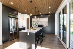 a modern kitchen with stainless steel appliances and wood ceilinging, along with sliding glass doors leading to an outdoor deck