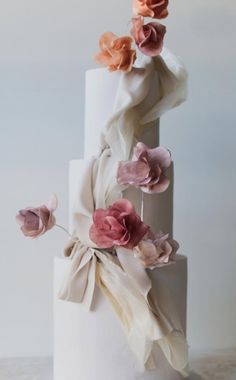 a three tiered white cake with pink and orange flowers on top