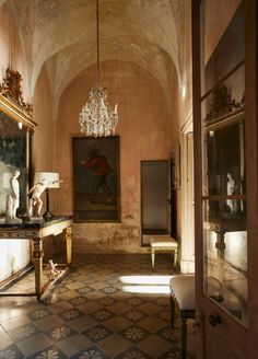 an ornate hallway with chandelier and paintings on the walls