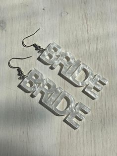 the bride and groom name earrings are made out of plastic letters on wooden planks