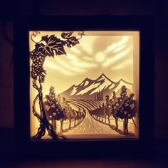 a paper cut landscape with trees and mountains in the background is lit up at night