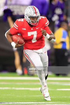 a football player running with the ball in his hand and wearing a red jersey, white helmet