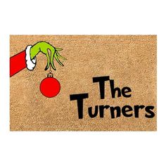 a door mat with the words'the turners'and a hand holding a christmas ornament