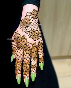 a woman's hand decorated with henna and green nail polishes on it